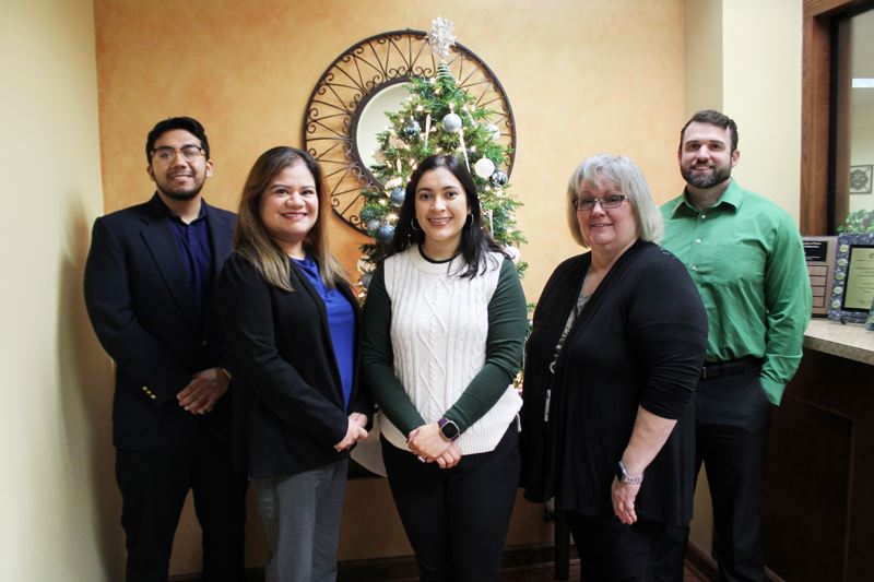 Group photo in Finance office with plaques sitting on a counter.