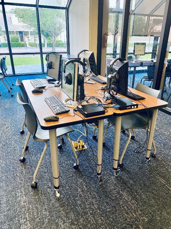 Four new computer tables, each with a computer sitting on top.