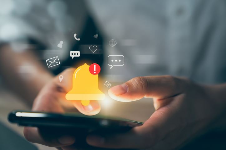 Close up of hands holding a phone with an alert icon illustration hovering above the screen