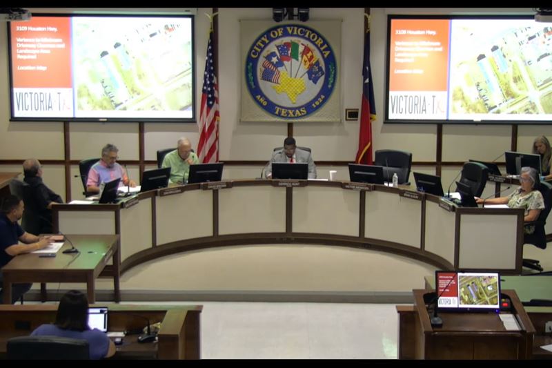 Planning commission members seated at council dais while projector displays powerpoint with map
