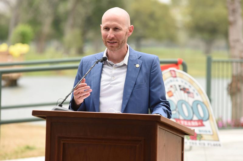 Man speaking at a podium with the duck pond in the background