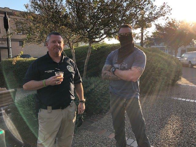 A police officer poses for a photo with a man with sleeve tattoos at the City Hall courtyard.