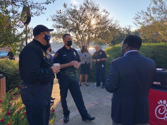 Two police officers talk with a man in a suit at the City Hall courtyard.