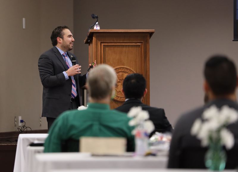 City manager Jesús Garza holds microphone and addresses seated attendees at Community Center annex.
