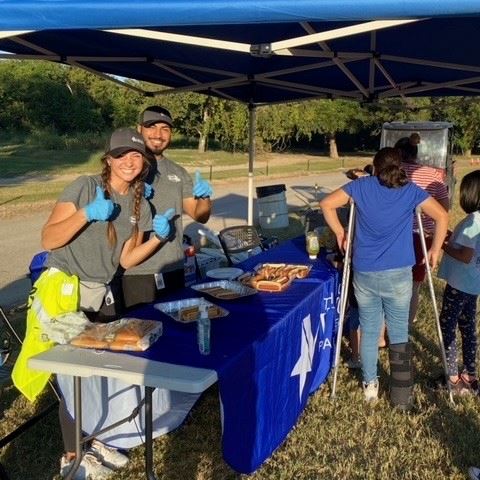 Parks & Recreation staff in T-shirts serve hot dogs outside