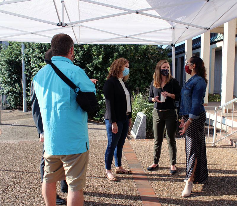 People visit under a canopy at the City Hall courtyard.